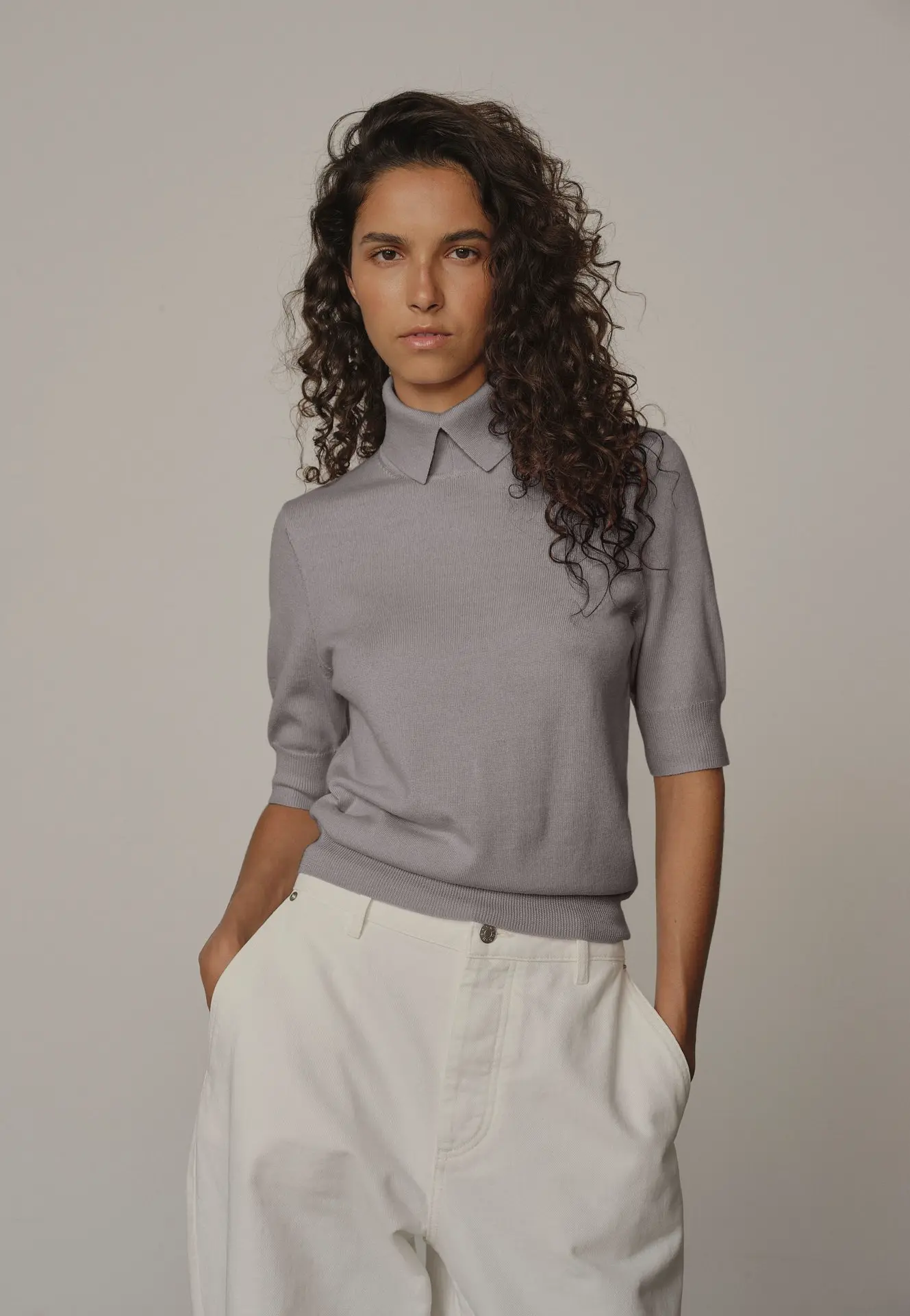 Jeune Femme portant un jeans blanc et pull gris avec col