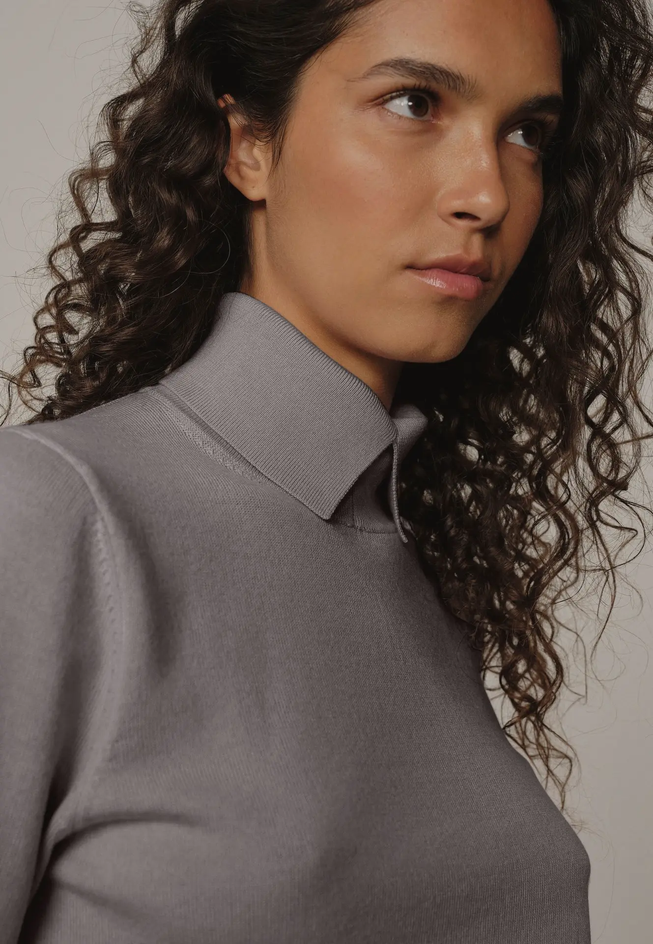 Détails d'un col de pull gris porté par une jeune femme