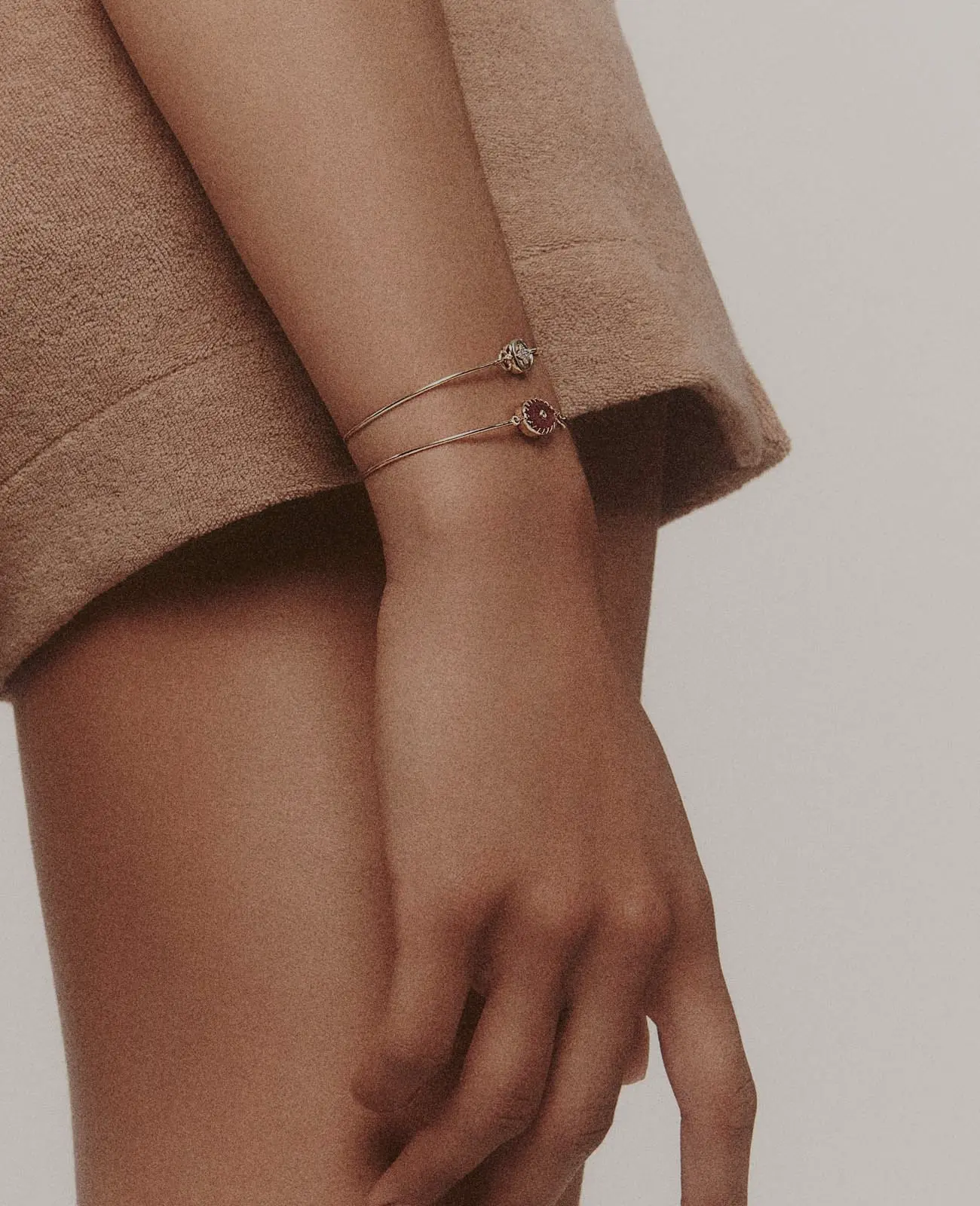 Poignet de femme portant deux bracelet en or et pierre précieuse